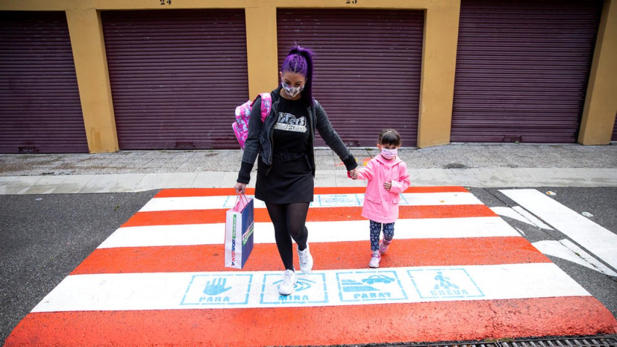 Una mare i la seva filla creuant un pas de vianants escolar.