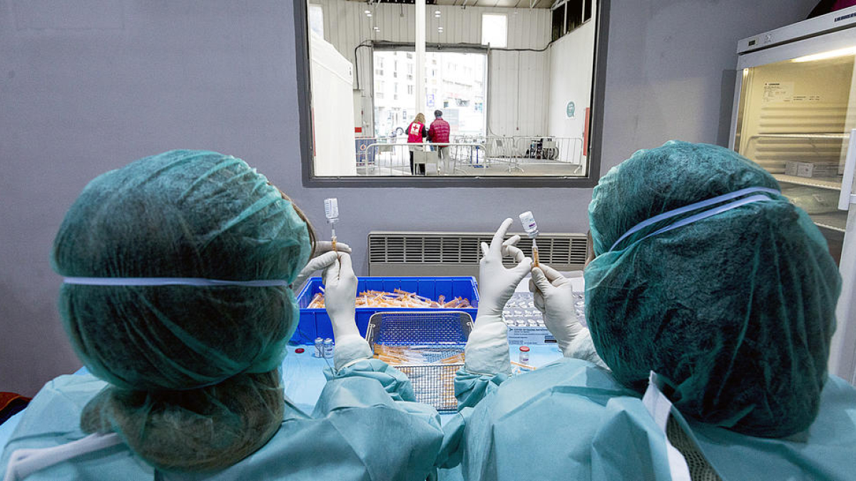 Dos sanitaris preparant dues dosis de la vacuna contra la Covid-19 al recinte de l'antiga plaça de braus.