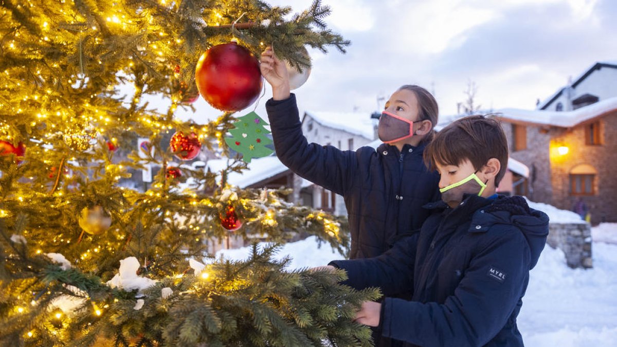 Dos nens guarnint l'avet a la plaça de les Fontetes.