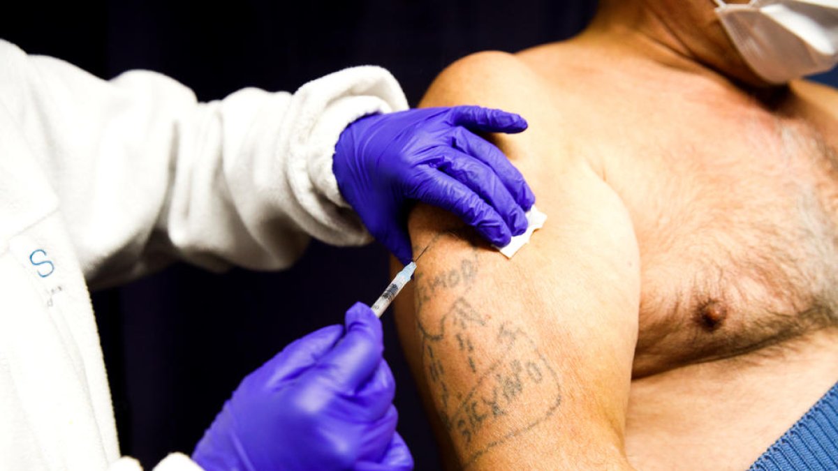 Un home rebent la tercera dosi del vaccí.