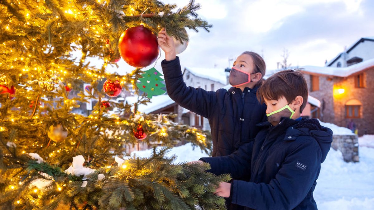 Dos infants decorant l'avet.