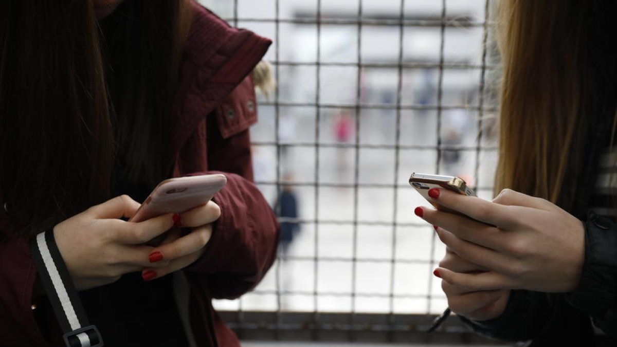 Dues noies consultant el telèfon mòbil