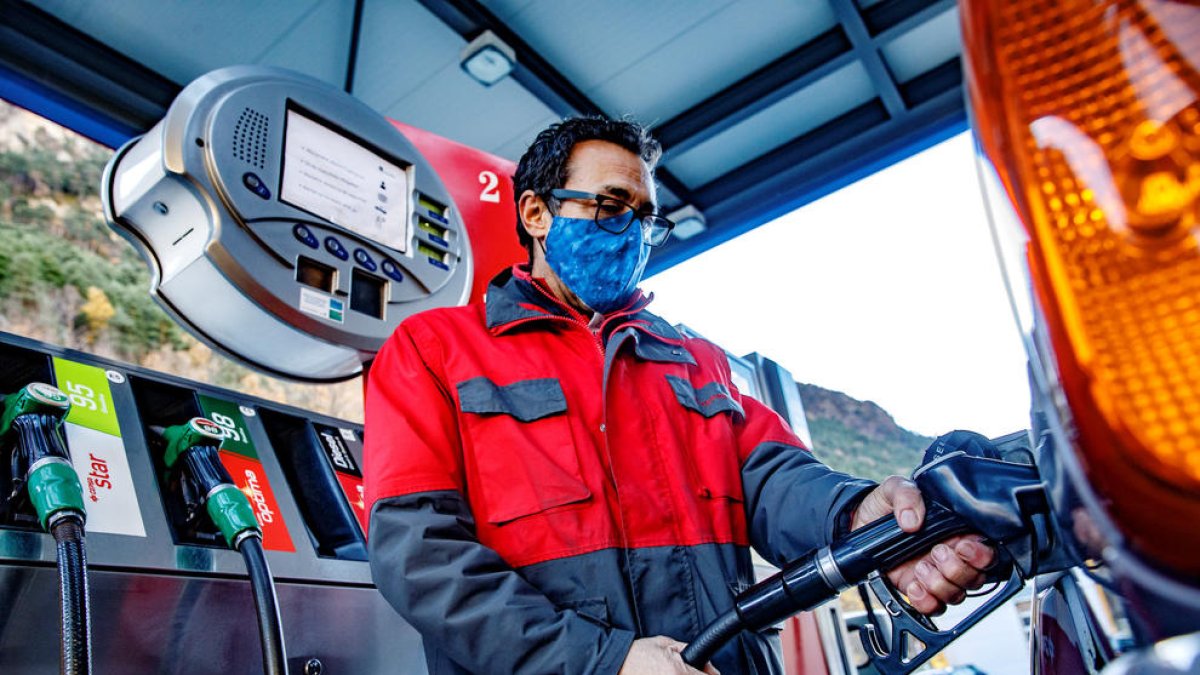Un treballador d'una benzinera mentre reposta carburant.
