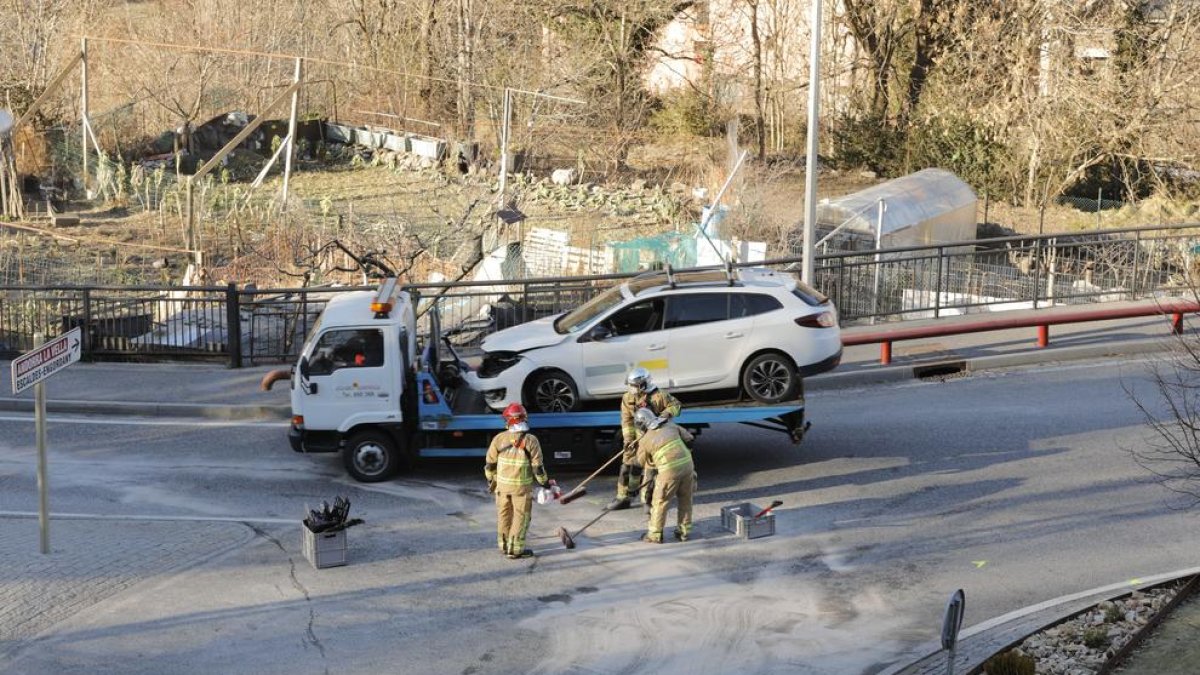 Una grua retira el taxi accidentat mentre els bombers netegen la calçada