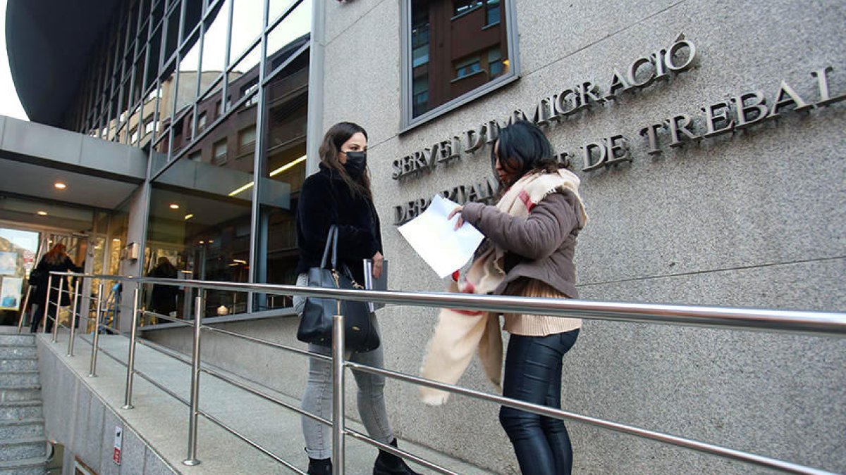 Dues persones a les portes de les oficines d'Immigració i Treball.