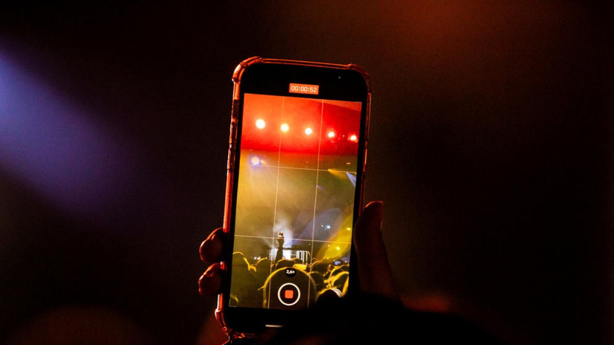 Una persona gravant un vídeo amb el mòbil en un concert.