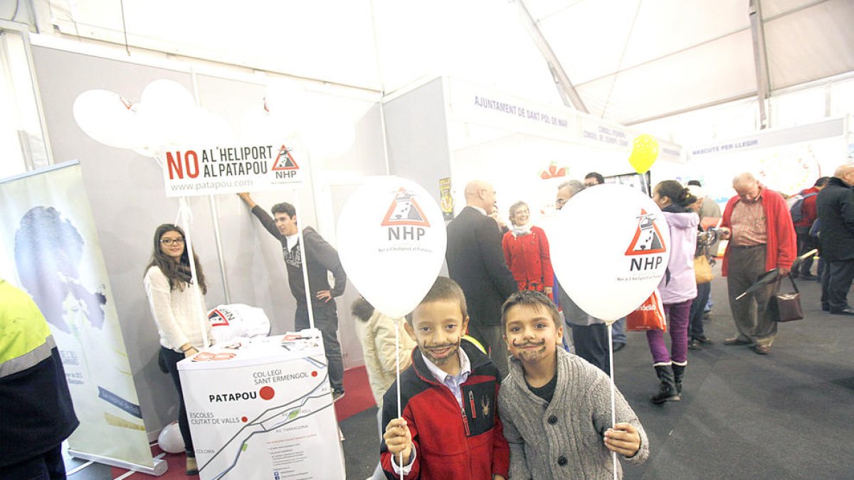 Dos nens davant el punt de recollida de signatures contra l'heliport situat a la fira de la capital.