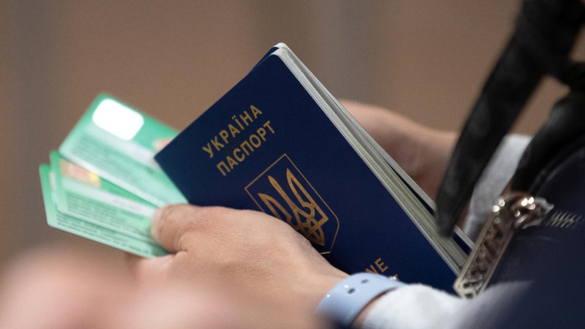 Una dona amb un passaport d'Ucraïna i d'altres documents.