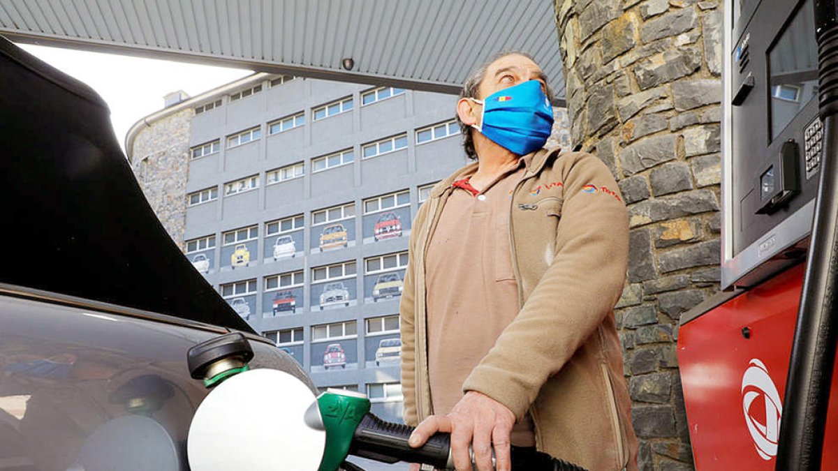 Un treballador d'una benzinera omple un dipòsit.