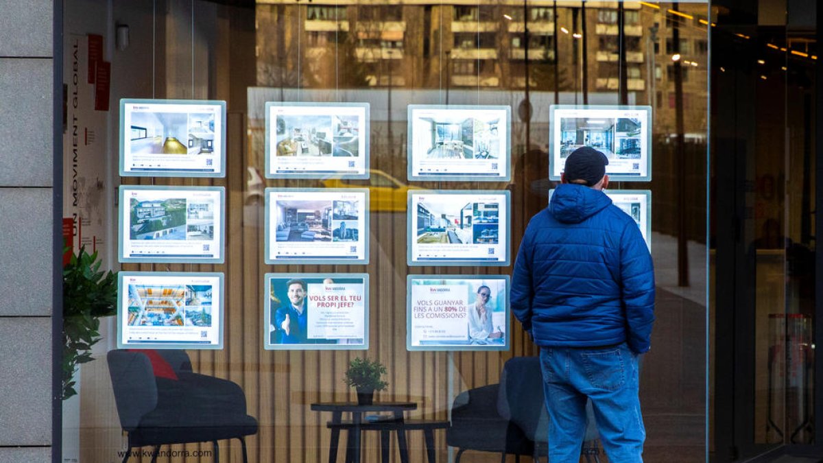 Un home davant una agència immobiliària.