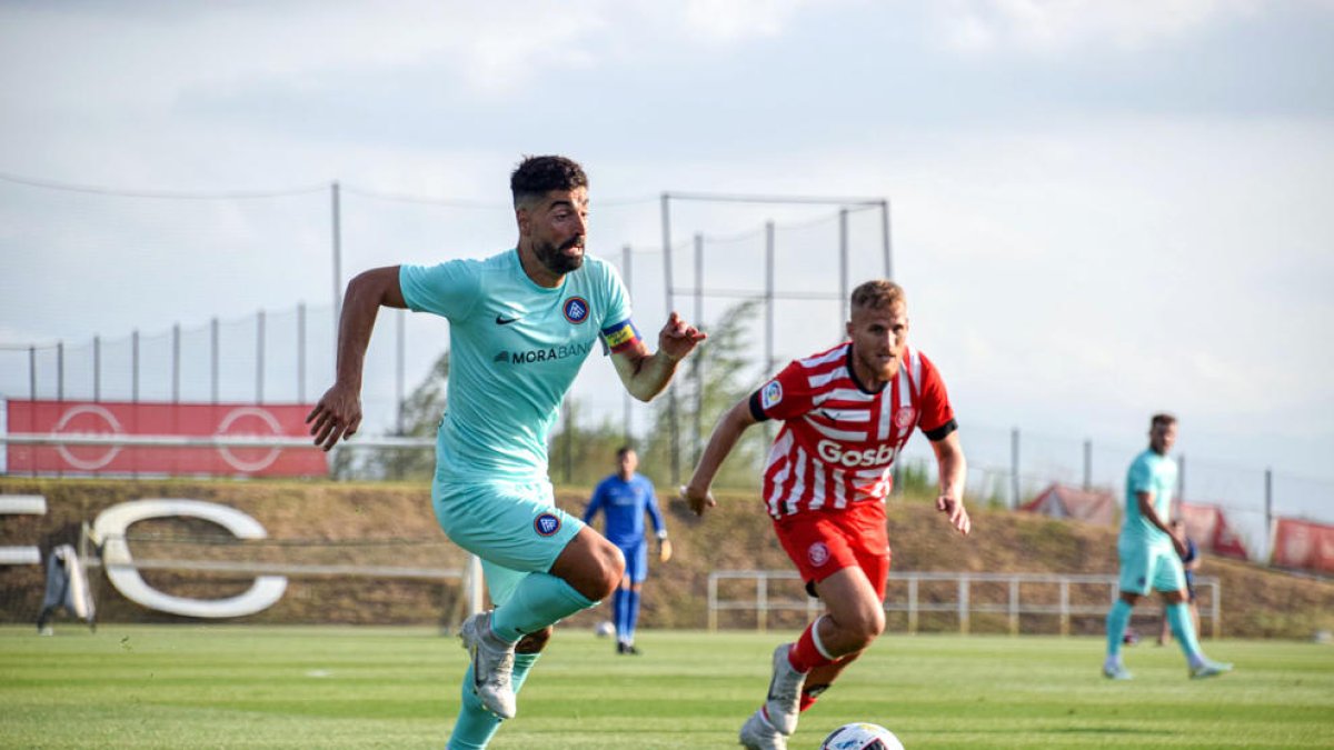 Carlos Martínez lluita per la pilota amb Samu Saiz, jugador del Girona FC, ahir a La Vinya.