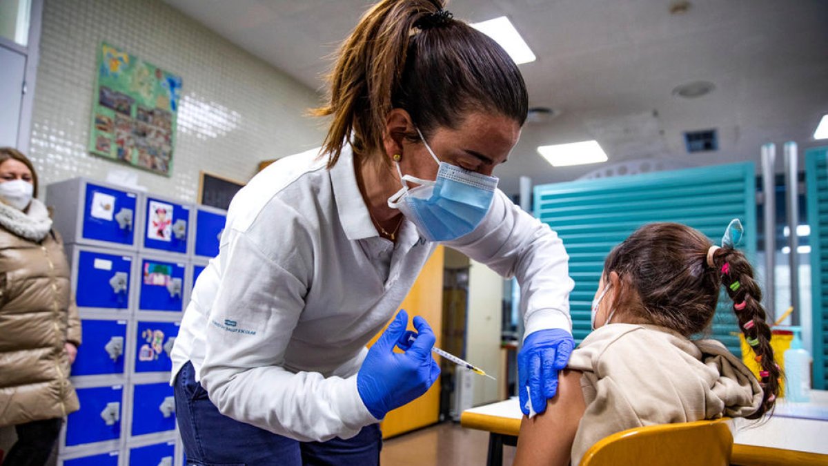 Una infermera administra el vaccí pediàtric a una nena.