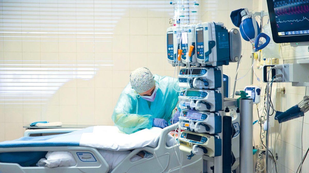 Un treballador de l'hospital atenent un pacient amb covid a la unitat de cures intensives.