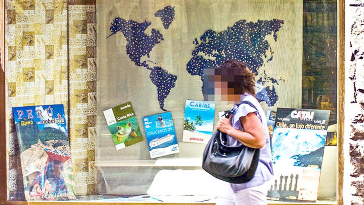 Una dona passeja davant d'una agència de viatges.