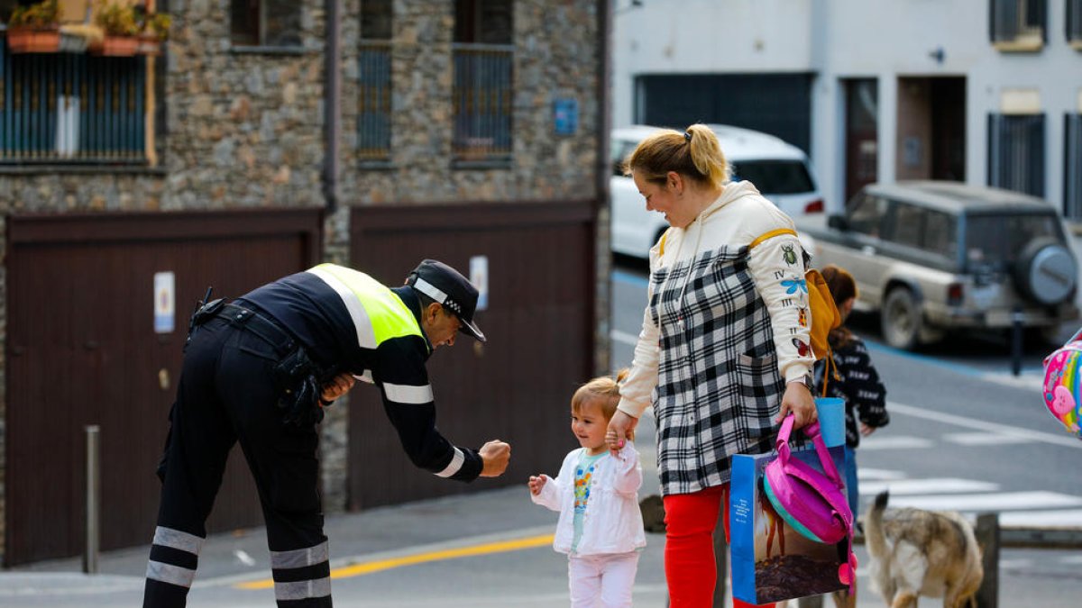 Un agent de circulació saludant un escolar.