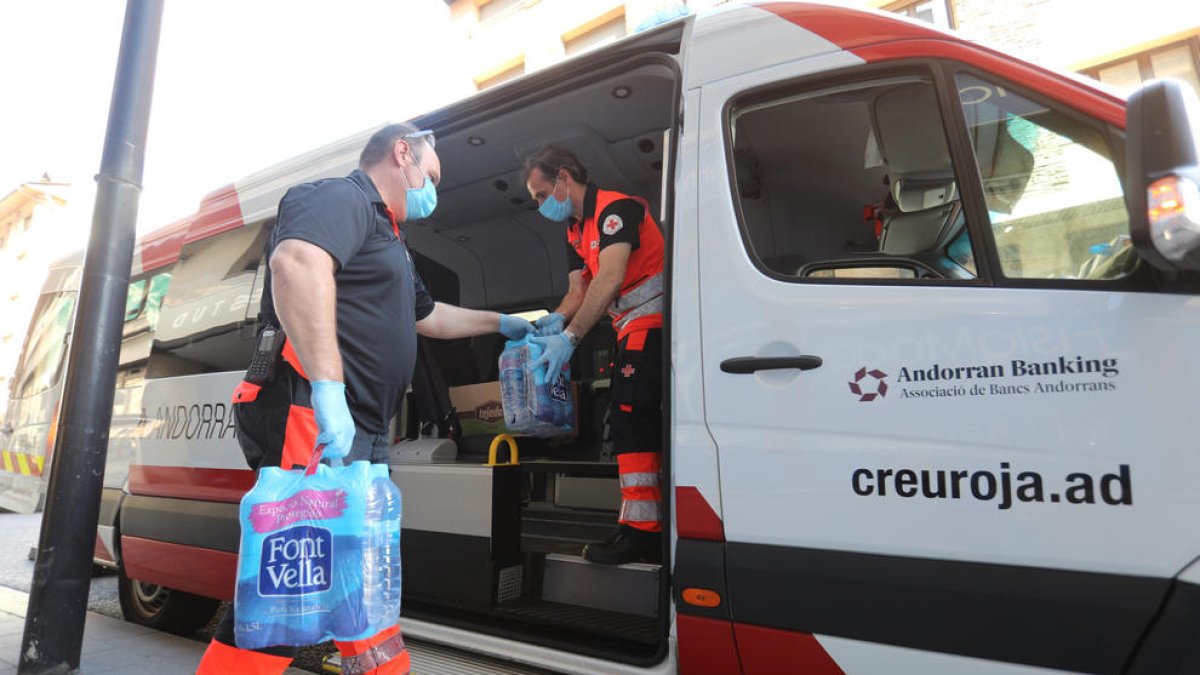 Dos treballadors de la Creu Roja carreguen ampolles d'aigua.