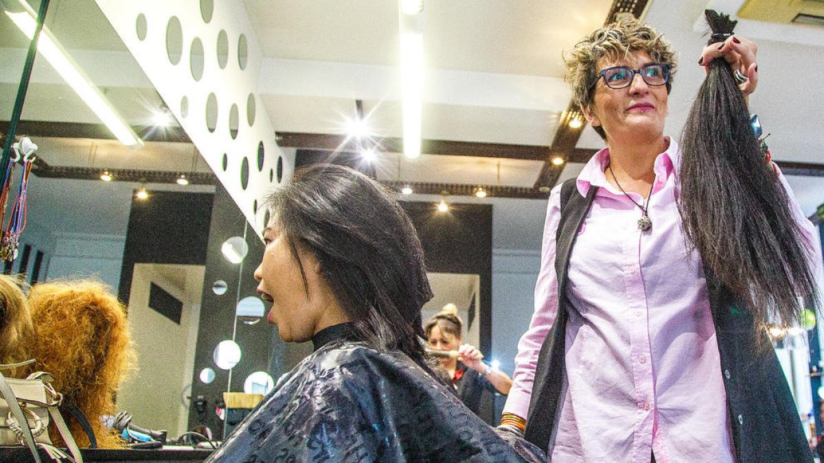 Una dona tallant-se el cabell per fer la donació.