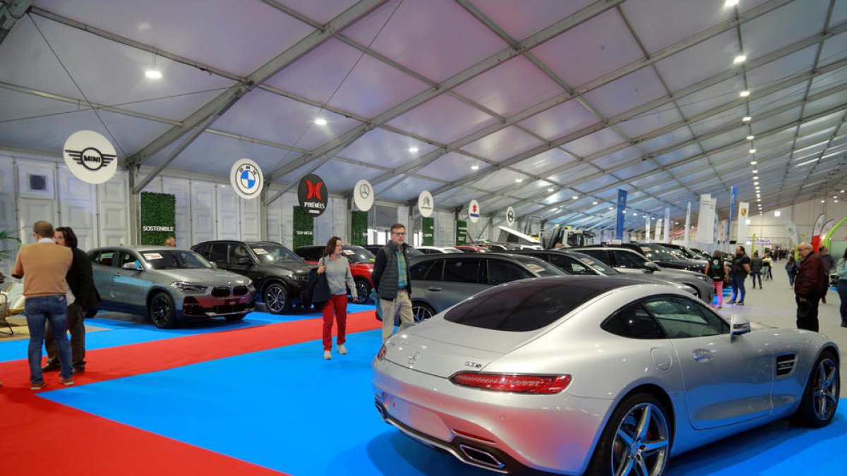 Diverses persones contemplen els turismes en una fira de vehicles