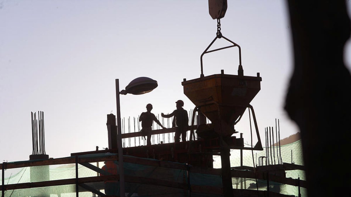 Uns treballadors en una obra per aixecar un edifici.