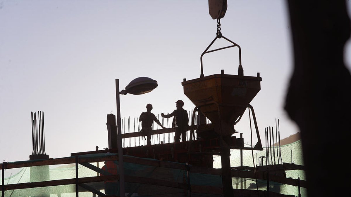 Uns treballadors en unes obres per aixecar un edifici.