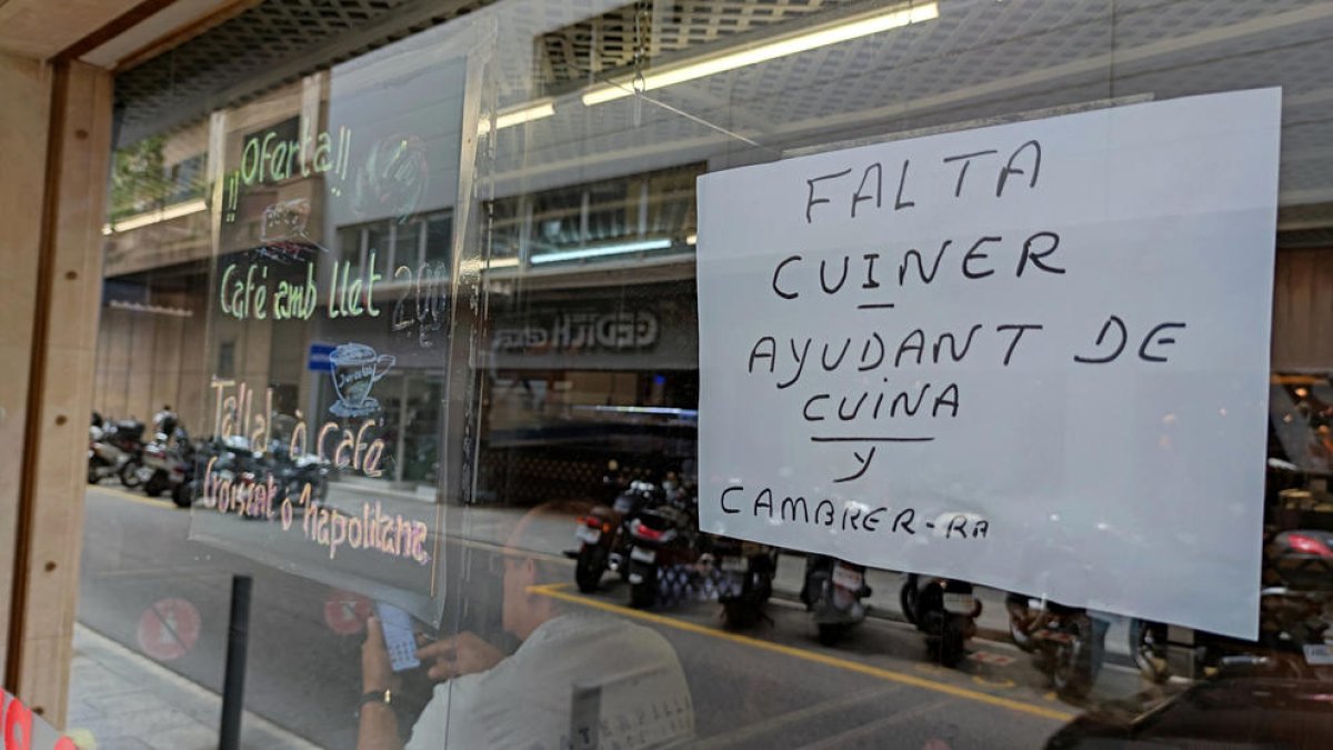 Un avís demandant treballadors a la porta d'un establiment de restauració.