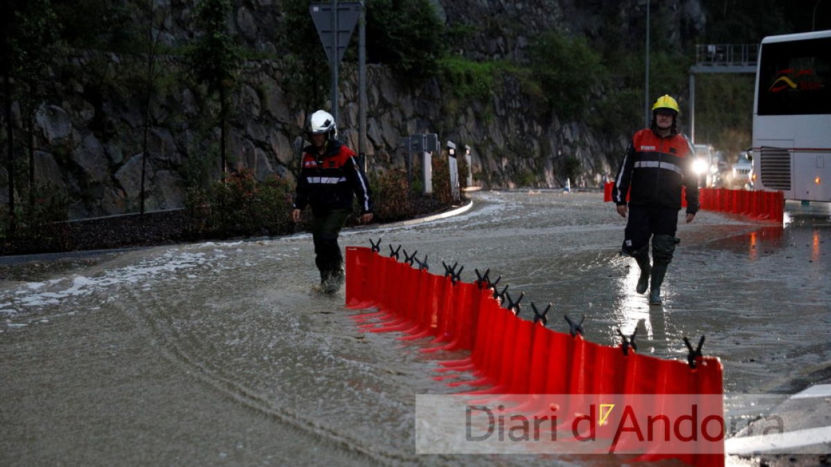Bombers treballant a la rotonda de la Portalada per contenir l'aigua del torrent