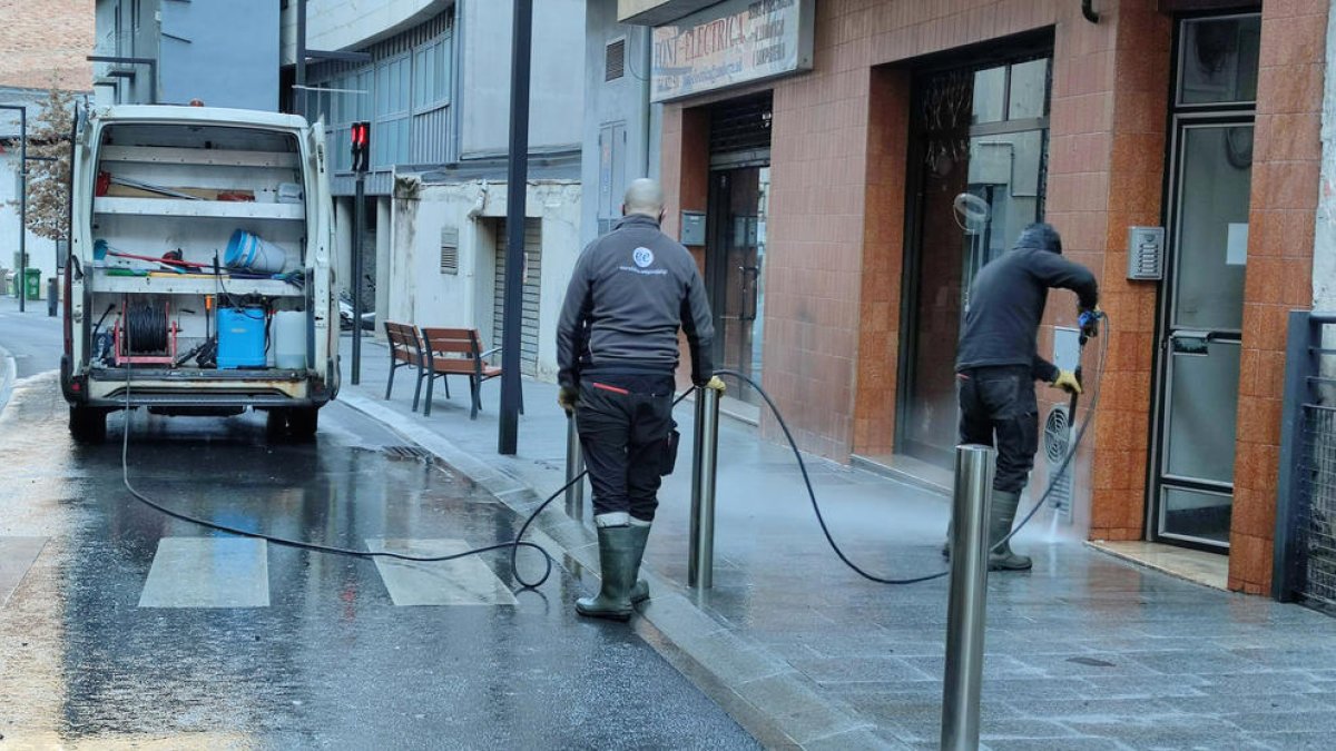 Treballadors del comú netejant els carrers de Sant Julià.