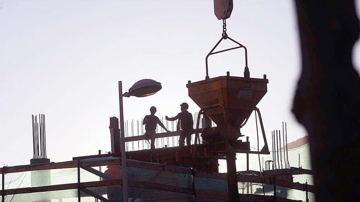 Uns treballadors en una obra per aixecar un edifici.