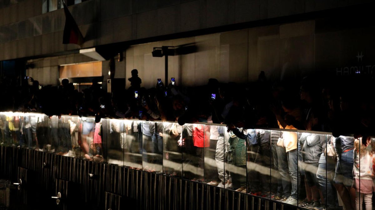 Turistes, de nit, davant les fonts de color.