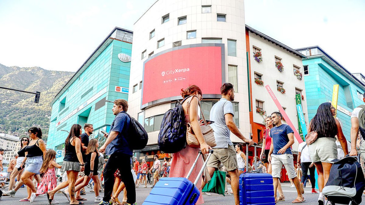 Turistes carregats amb maletes al carrer de la Unió d'Andorra la Vella.