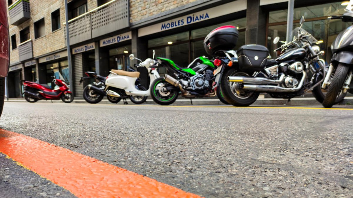 Un aparcament de zona taronja amb motos al fons.