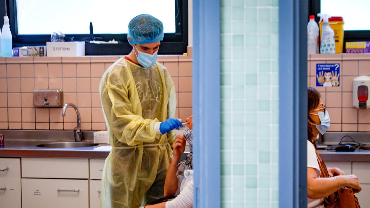 Un sanitari fent un test de covid a una pacient.