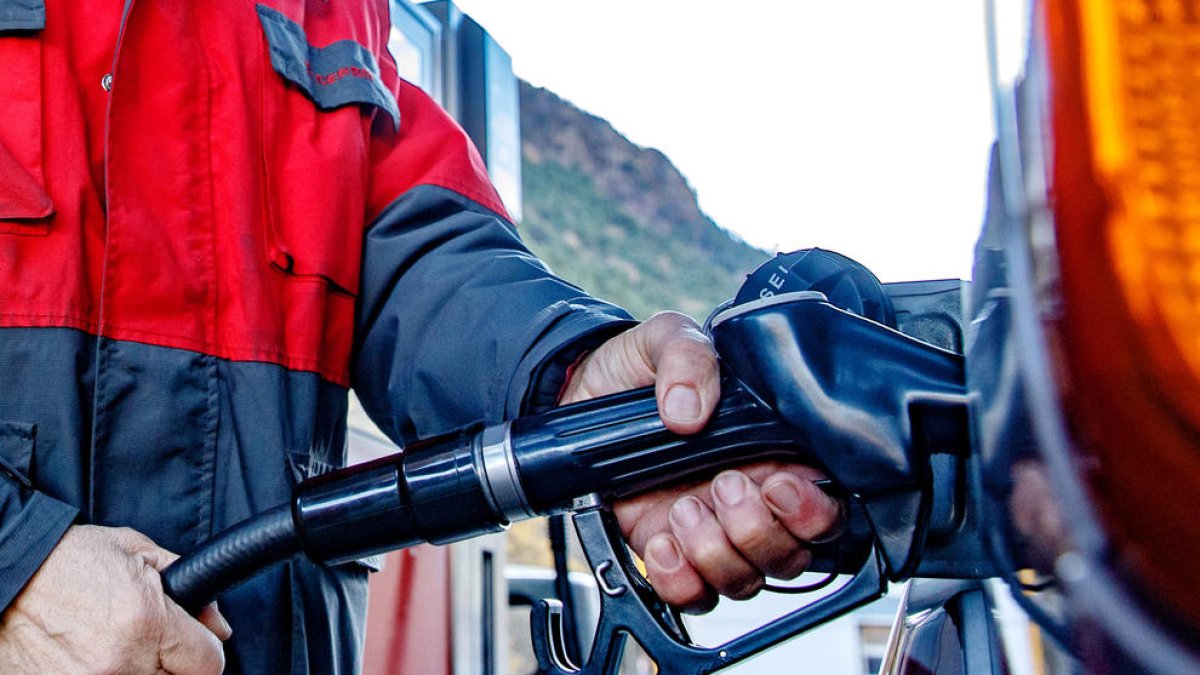 Un treballador carrega el dipòsit d'un vehicle.