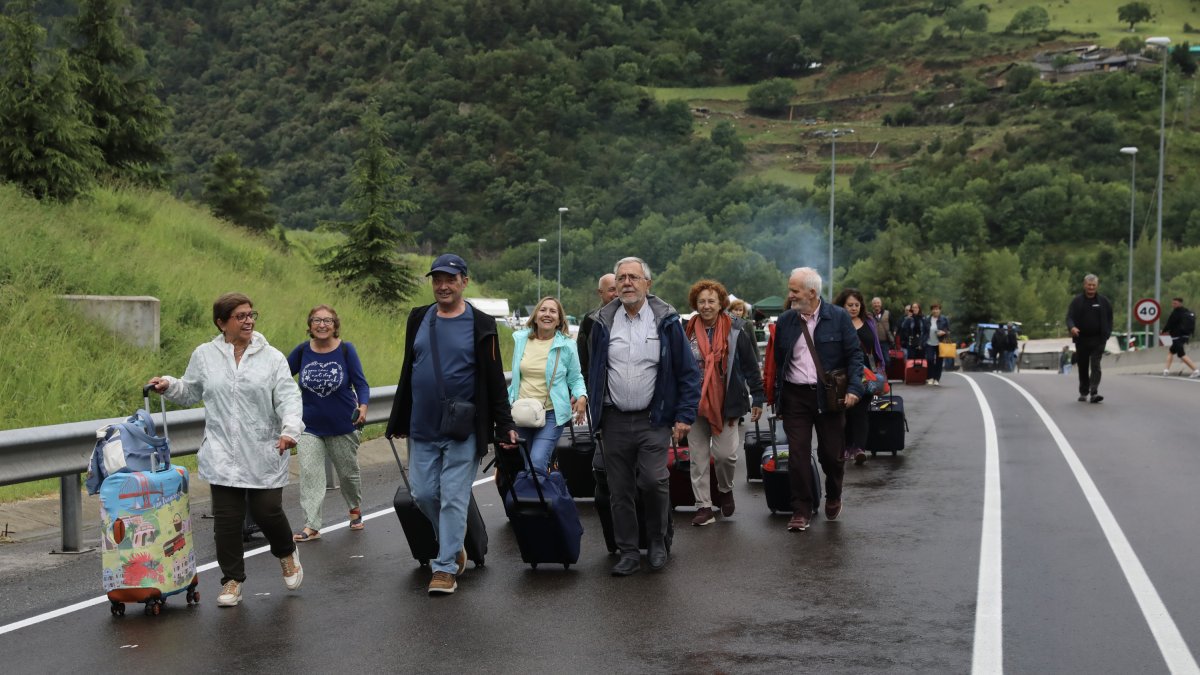Viatgers d'un autobús passen caminant la rotonda bloquejada per Revolta Pagesa per agafar un altre vehicle per entrar a Andorra