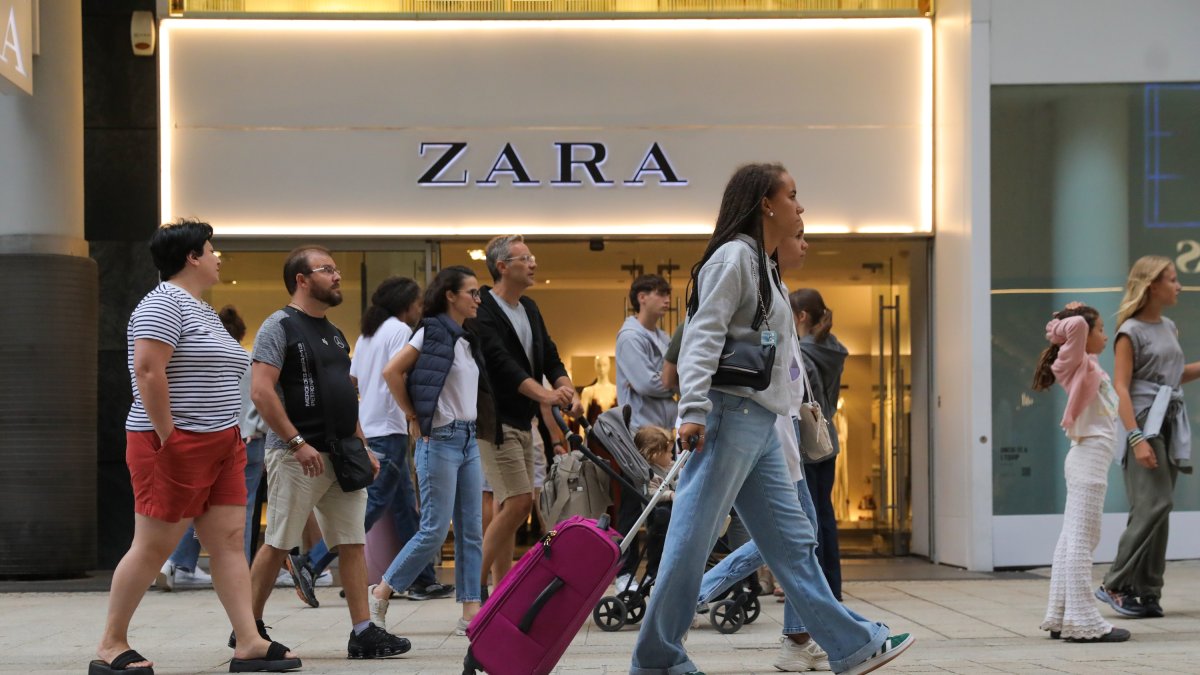 Una jove amb una maleta a l’eix comercial.