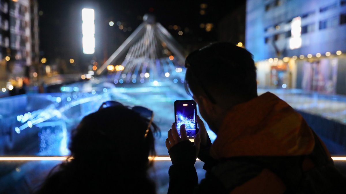 Una parella grava en vídeo l'espectacle musical de les fonts lluminoses del riu Valira