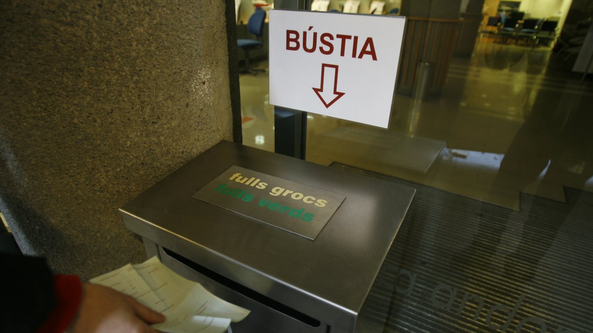 Un usuari diposita un full groc a la bústia de la CASS.