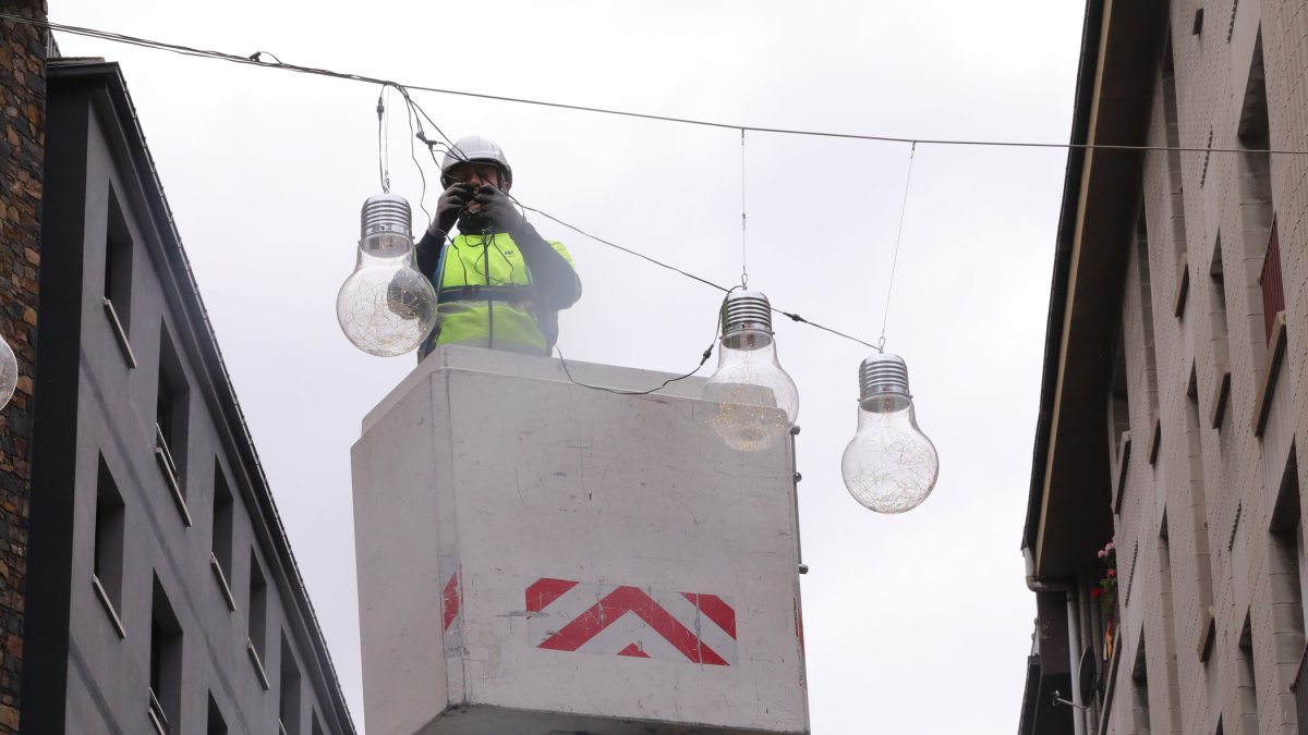 Un operari del comú penjant garlandes de Nadal.