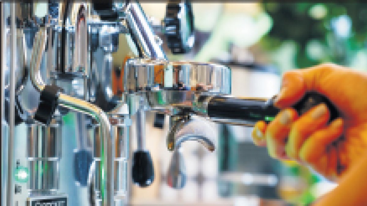 Un treballador manipulant la cafetera d’un establiment.