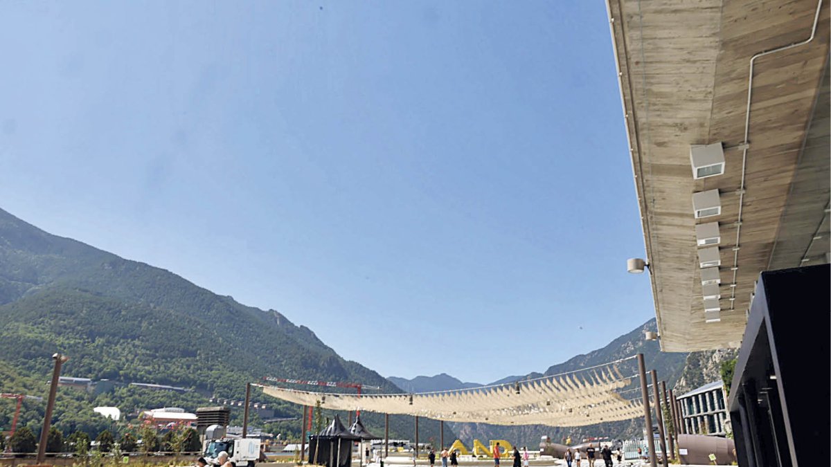 Residents i turistes passegen per una plaça del Poble gairebé sense zones d’ombra.