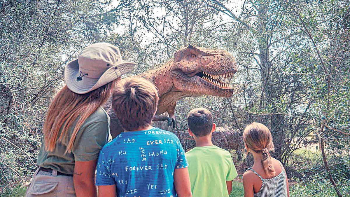 Un grup de nens contempla un tiranosaure rex a Dinosaurland.