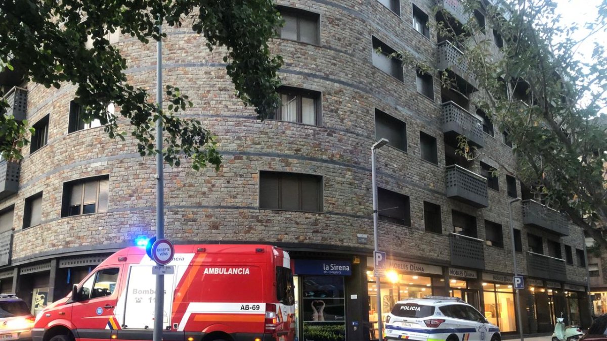 L'ambulància dels bombers i un vehicle de policia davant l'edifici on es troba el pis de la persona afectada.