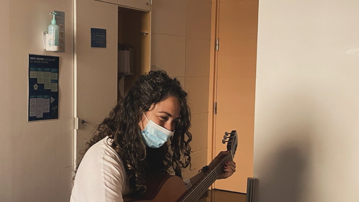 La musicoterapeuta Laia Font, tocant la guitarra a una persona a la Unitat de Cures Pal·liatives de l'hospital
