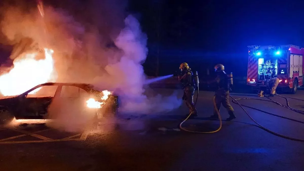 Bombers intervenint amb el cotxe incendiat.