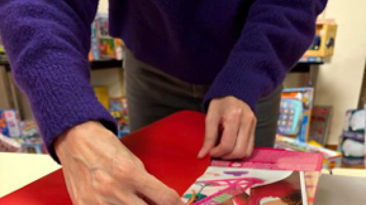 Una persona de Càritas Andorra, embolicant un regal.