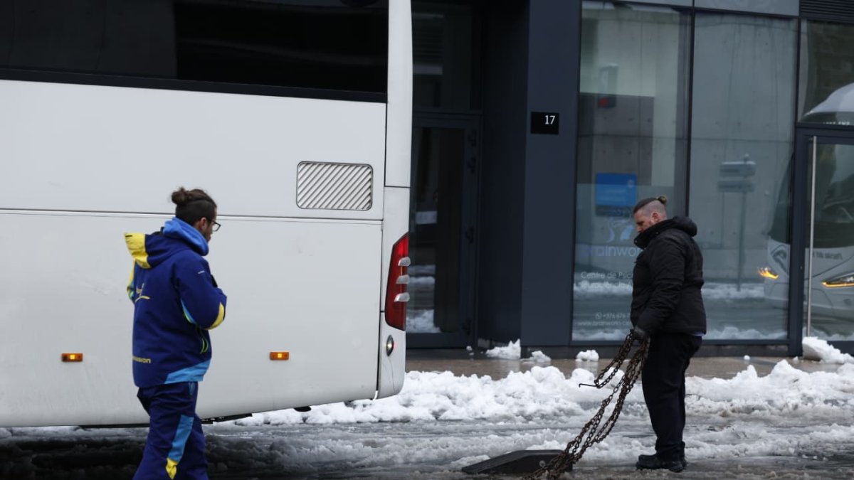 Dues persones posant cadenes a un autocar.
