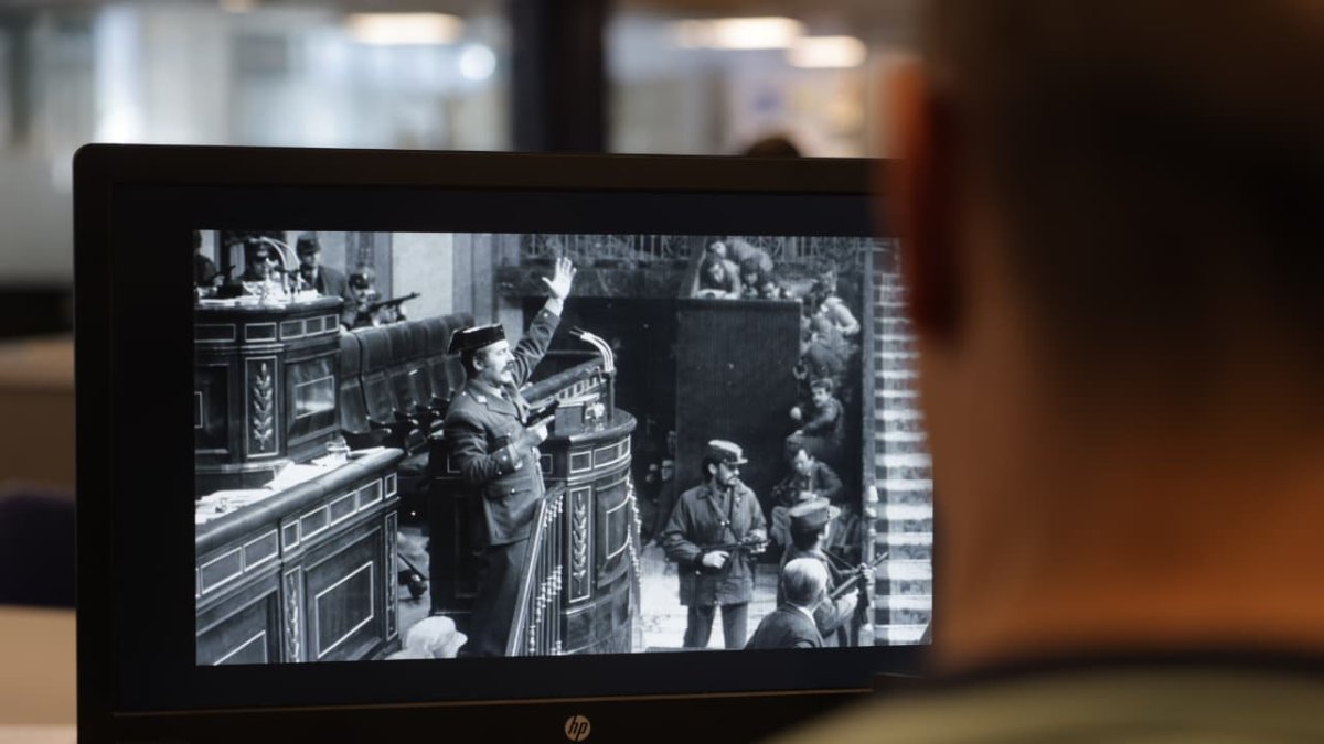 Un redactor del Diari mirant la imatge del cop d'Estat amb el general Tejero al Congrés dels Diputats espanyol.