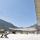 Residents i turistes passegen per una plaça del Poble gairebé sense zones d’ombra.