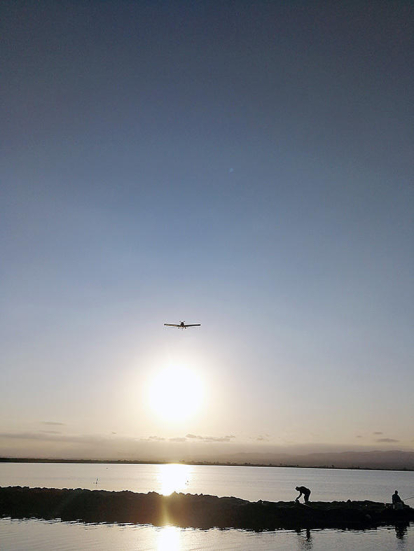 Dos pescadors treballen durant la posta de sol mentre una avioneta fumigadora passa pels camps d'arròs. En Cerni Obiols va captar aquesta imatge mentre estava de vacances al Port de l'illa del Mar, a Deltebre.