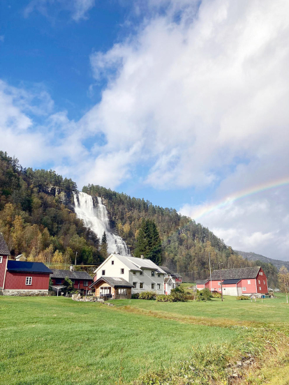 Instantània de la cascada de Trollafossen, situada a Voss, un municipi de Noruega. La grandiositat de la cascada, juntament amb les casetes als seus peus i l'arc de Sant Martí de fons, deixen un paisatge de somni.